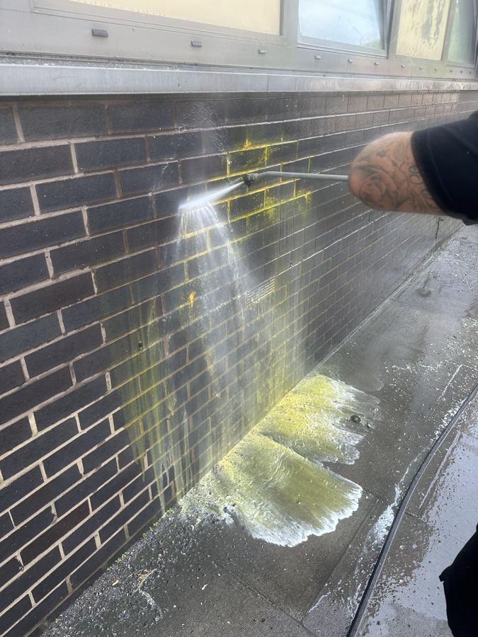 Graffiti being jet washed off a brick wall
