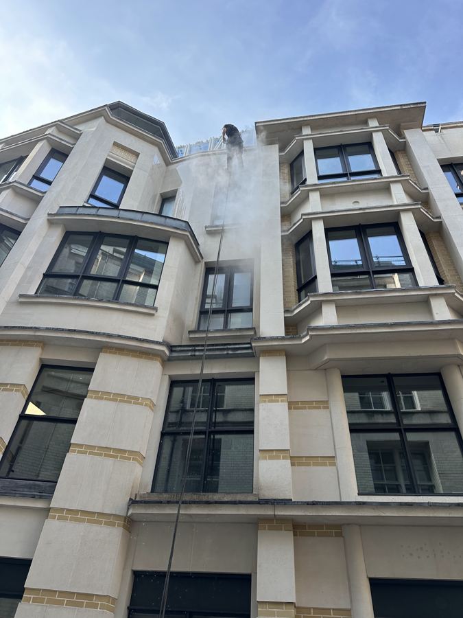 Rope access technicians cleaning a stone building façade
